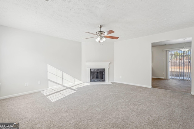 unfurnished living room featuring ceiling fan, carpet floors, and a textured ceiling