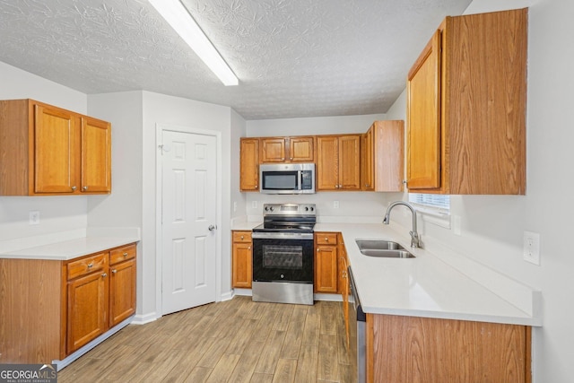 kitchen featuring sink, light hardwood / wood-style flooring, a textured ceiling, and appliances with stainless steel finishes