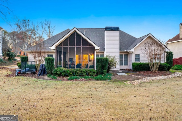 rear view of property featuring a sunroom and a lawn