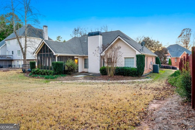 view of front of property with a sunroom, a front yard, and central AC