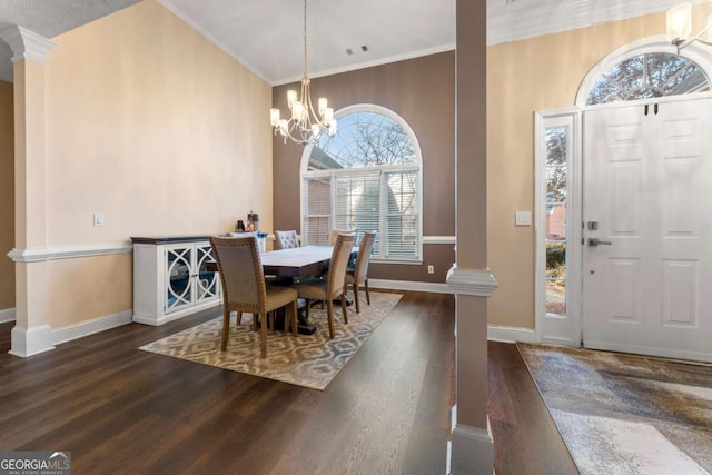 dining area featuring decorative columns, crown molding, dark hardwood / wood-style flooring, and an inviting chandelier