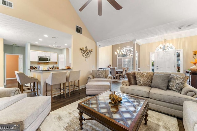 living room with hardwood / wood-style floors, ceiling fan with notable chandelier, and high vaulted ceiling