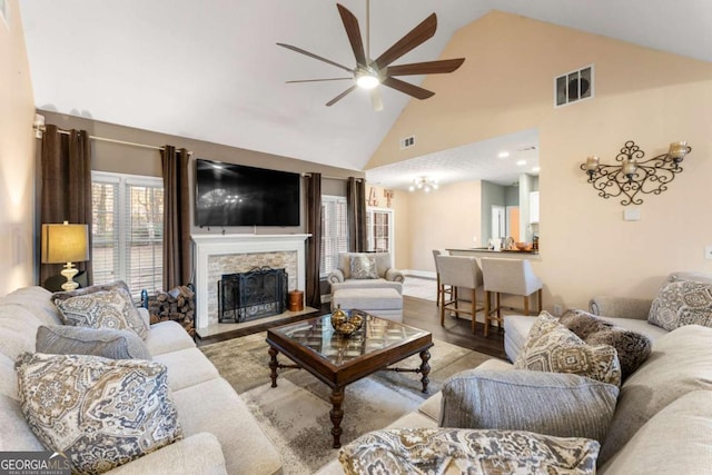 living room with a fireplace, light wood-type flooring, high vaulted ceiling, and ceiling fan