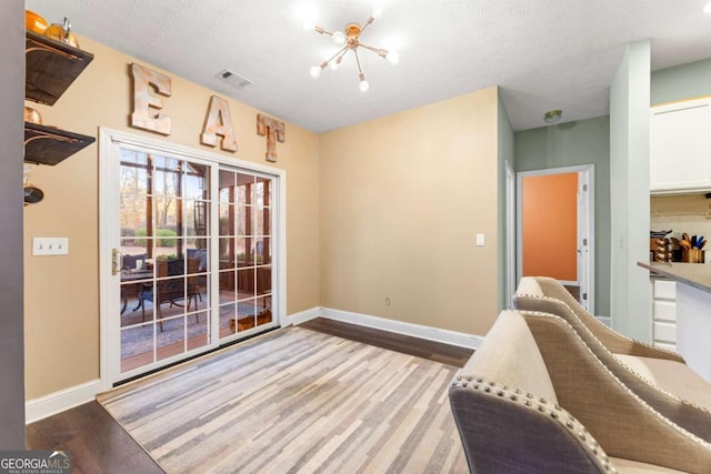 sitting room with a notable chandelier, light hardwood / wood-style floors, and a textured ceiling