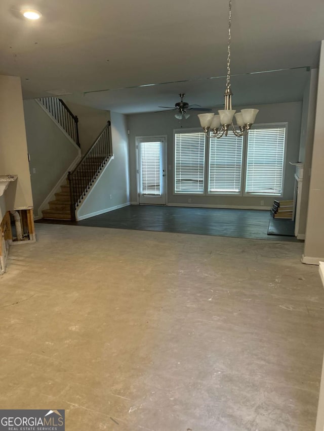 unfurnished living room with ceiling fan with notable chandelier and concrete floors