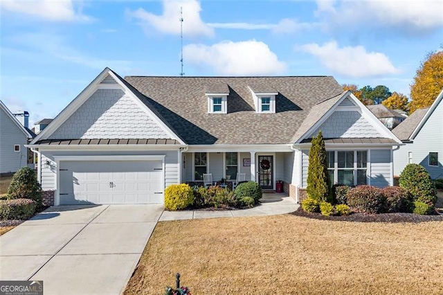 craftsman house featuring a porch, a garage, concrete driveway, a front lawn, and a standing seam roof