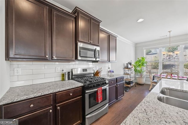 kitchen featuring dark brown cabinetry, stainless steel appliances, a sink, dark wood finished floors, and crown molding