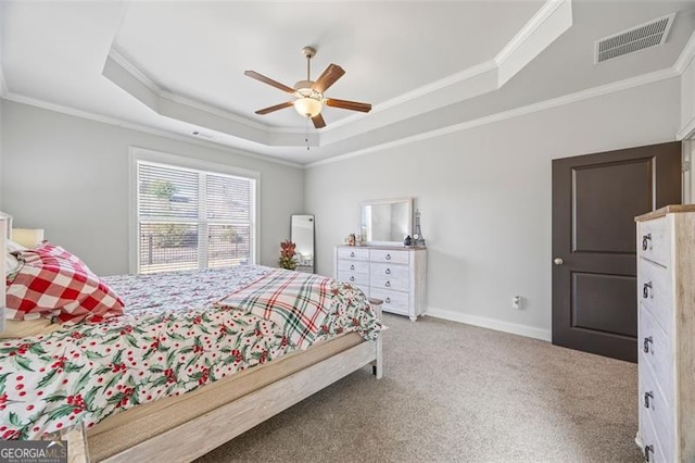 carpeted bedroom with baseboards, a tray ceiling, visible vents, and crown molding