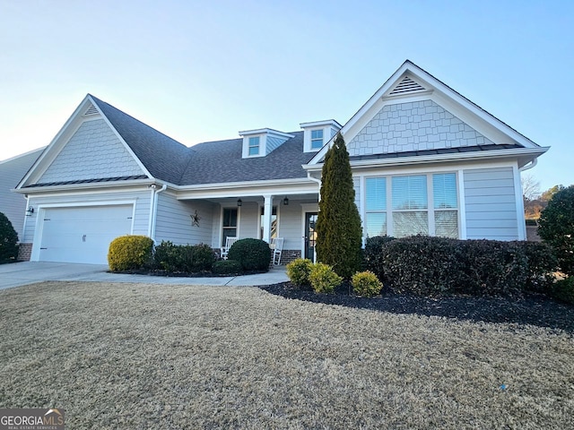 view of front of property with a garage, covered porch, driveway, and a shingled roof