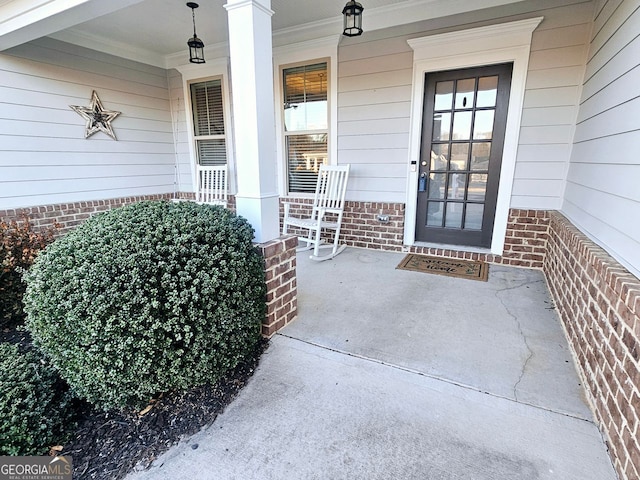 doorway to property featuring covered porch and brick siding