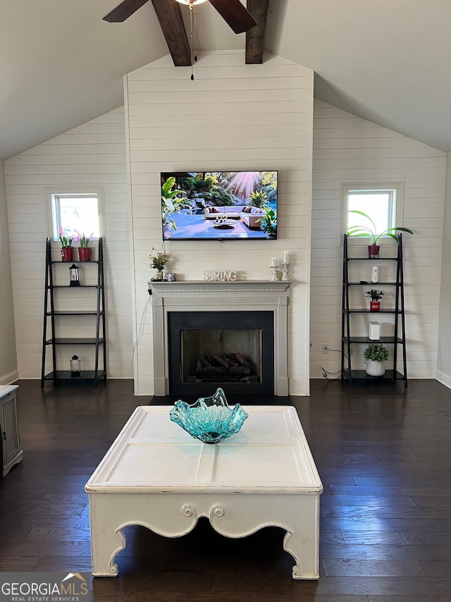 living area with vaulted ceiling with beams, dark wood-style floors, and a fireplace