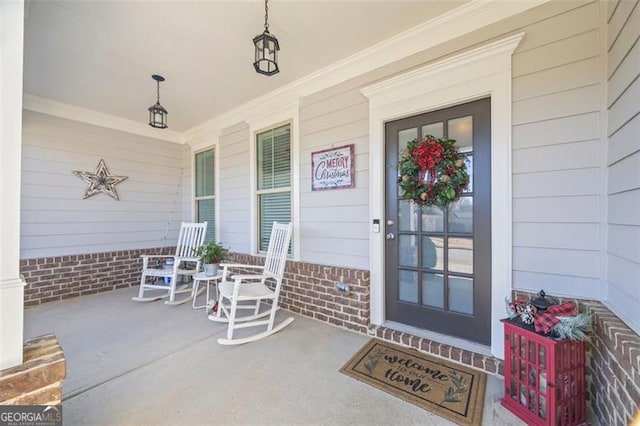 view of exterior entry with a porch and brick siding