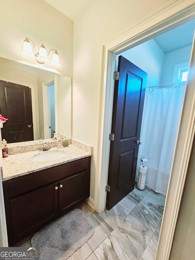 bathroom with marble finish floor, curtained shower, and vanity