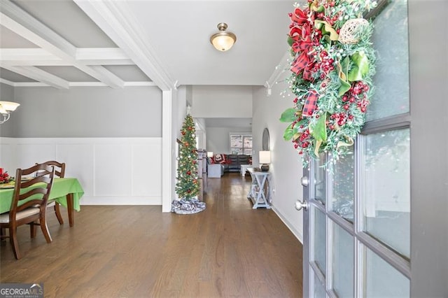 entryway with a decorative wall, coffered ceiling, wood finished floors, wainscoting, and beam ceiling