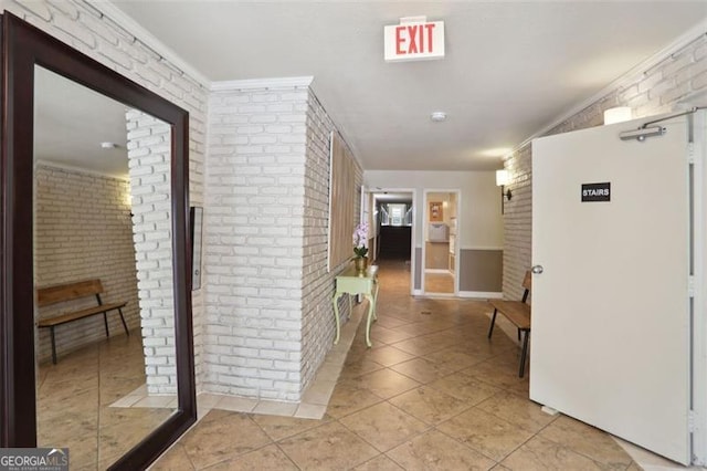 corridor featuring light tile patterned flooring, crown molding, and brick wall