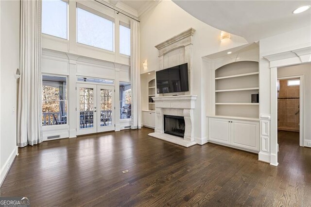 unfurnished living room with dark hardwood / wood-style flooring, built in features, and french doors