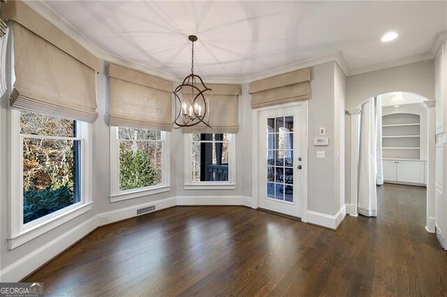 unfurnished dining area featuring a chandelier, dark hardwood / wood-style flooring, and crown molding