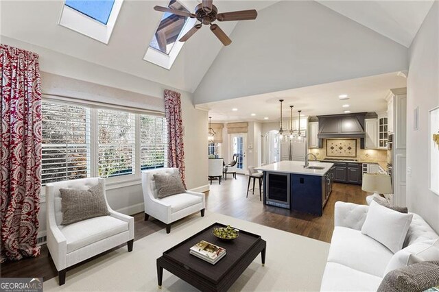 living room featuring high vaulted ceiling, ceiling fan with notable chandelier, sink, dark hardwood / wood-style floors, and beverage cooler