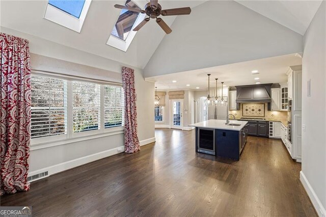 kitchen featuring pendant lighting, a kitchen island with sink, high vaulted ceiling, dark wood-type flooring, and custom range hood