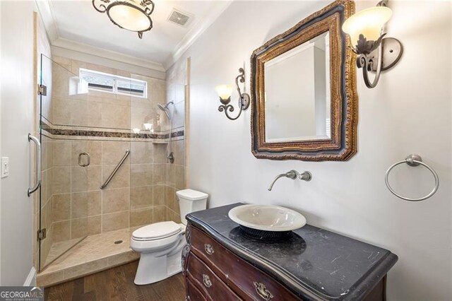 bathroom with wood-type flooring, vanity, a shower with door, and ornamental molding