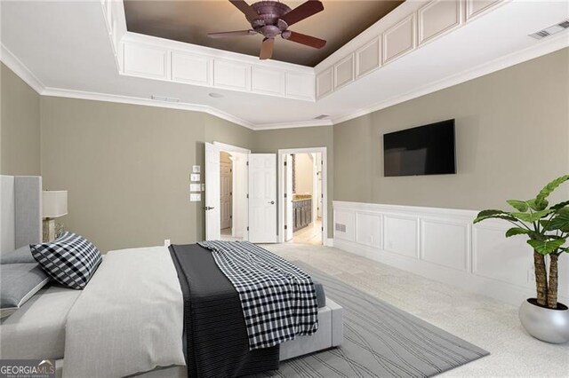 carpeted bedroom with ensuite bath, ceiling fan, and ornamental molding