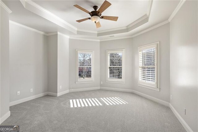 spare room with ceiling fan, a raised ceiling, and light colored carpet