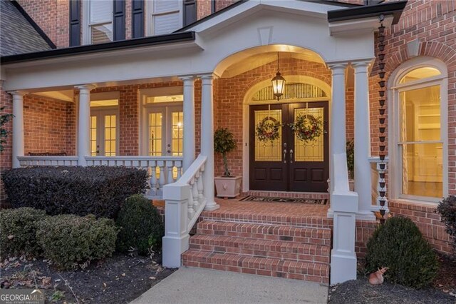 view of exterior entry featuring french doors and covered porch