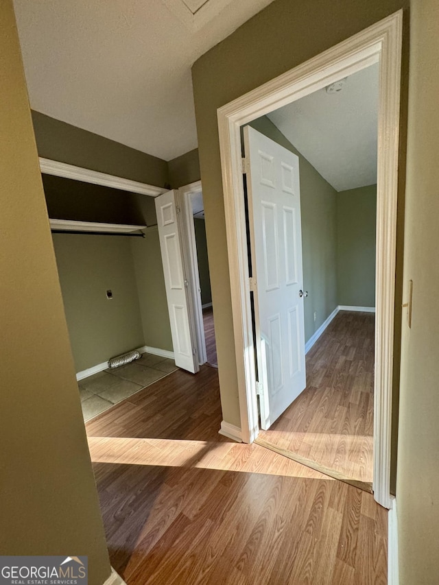 hallway featuring wood-type flooring and vaulted ceiling