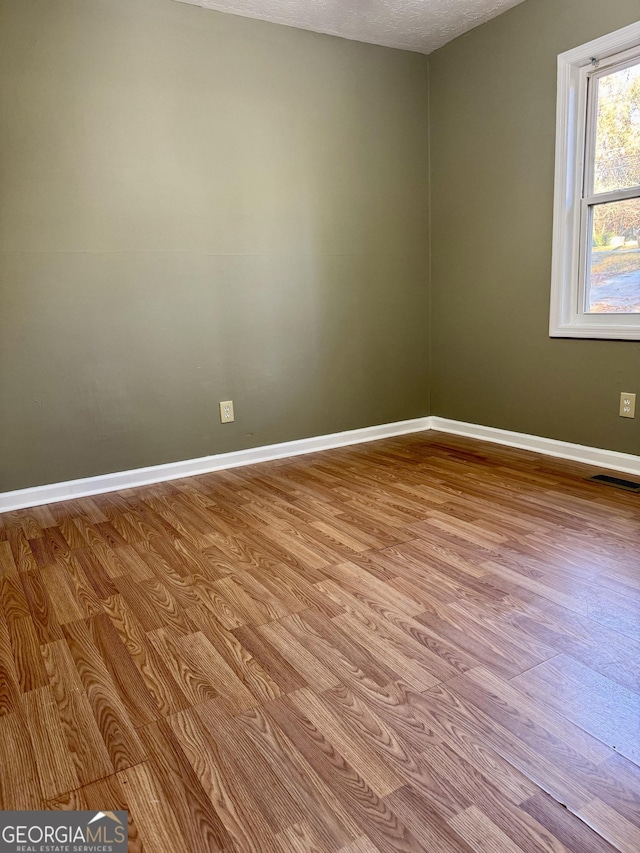 empty room featuring a textured ceiling and light wood-type flooring