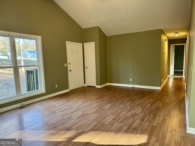 empty room featuring hardwood / wood-style flooring, a textured ceiling, and high vaulted ceiling