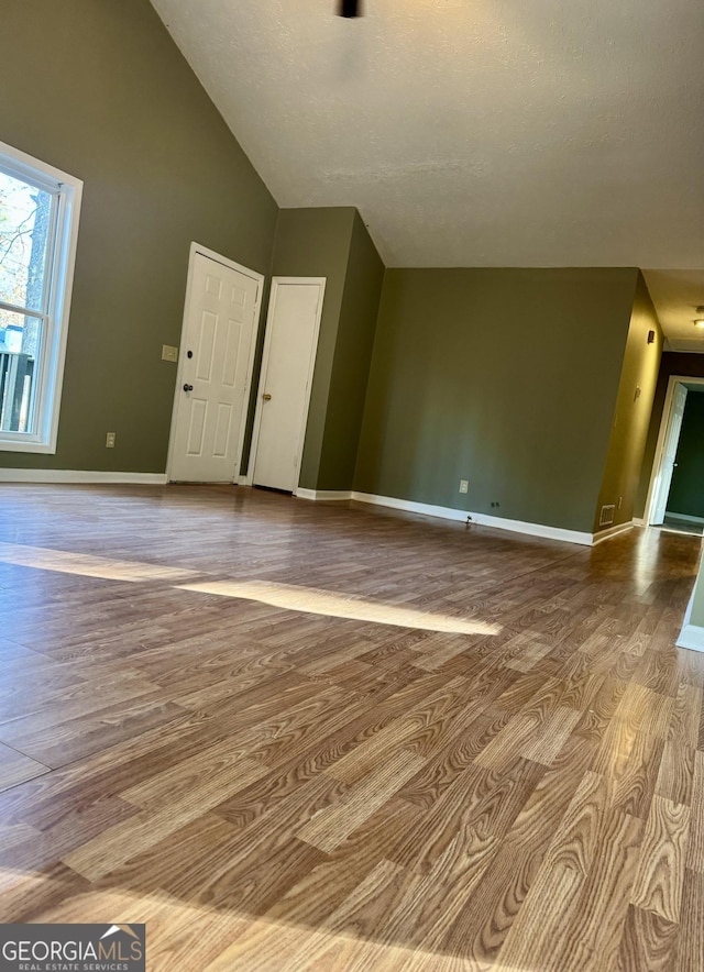 unfurnished living room featuring light hardwood / wood-style floors, a textured ceiling, and high vaulted ceiling