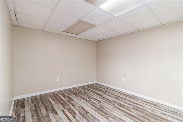 spare room with a paneled ceiling and wood-type flooring