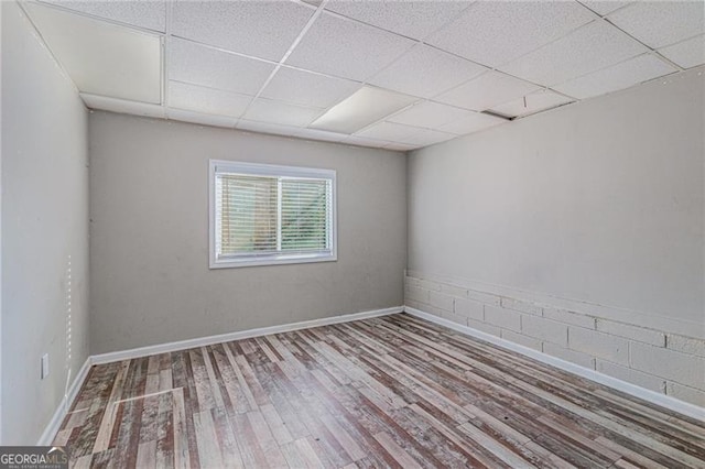 spare room with a drop ceiling and wood-type flooring