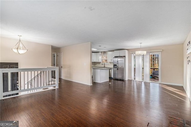 unfurnished living room with a textured ceiling, dark hardwood / wood-style flooring, and sink