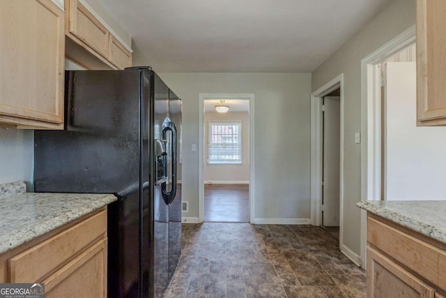 kitchen with black fridge, light brown cabinets, and light stone counters