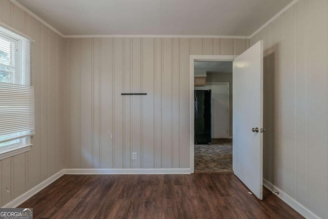 spare room featuring crown molding, wooden walls, and dark wood-type flooring