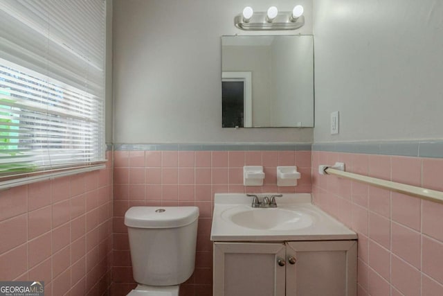 bathroom with vanity, toilet, and tile walls