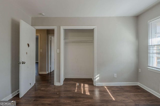 unfurnished bedroom featuring a closet and dark wood-type flooring