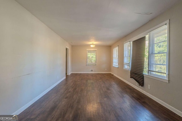 empty room with dark hardwood / wood-style floors and a wealth of natural light