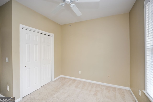 unfurnished bedroom featuring a ceiling fan, baseboards, a closet, and light carpet