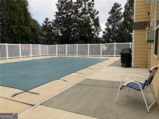 view of swimming pool featuring a fenced in pool, fence, a grill, and a patio area