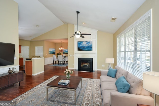 living room with ceiling fan, dark wood-type flooring, a fireplace, and vaulted ceiling