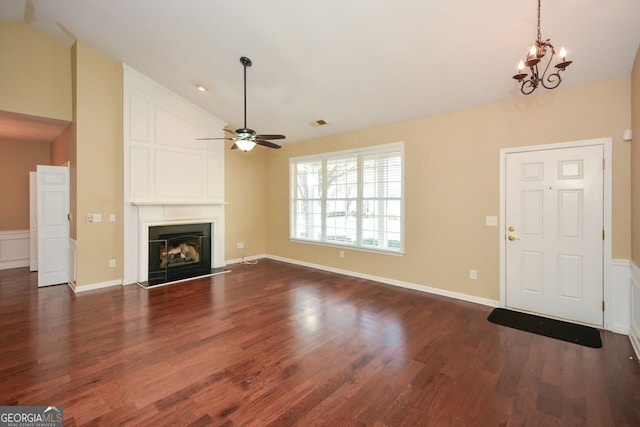 unfurnished living room featuring ceiling fan with notable chandelier, lofted ceiling, a fireplace, and dark wood-type flooring