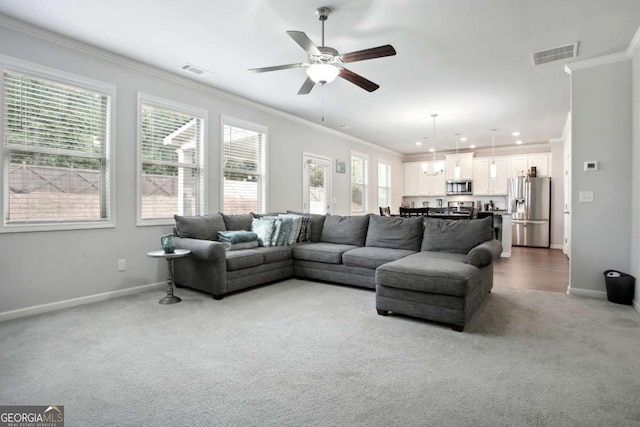 carpeted living room with crown molding and ceiling fan