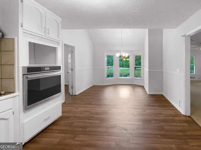 kitchen featuring dark hardwood / wood-style flooring, white cabinetry, stainless steel oven, and a textured ceiling