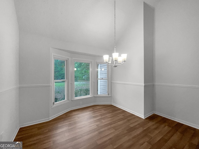 spare room with a chandelier and dark wood-type flooring