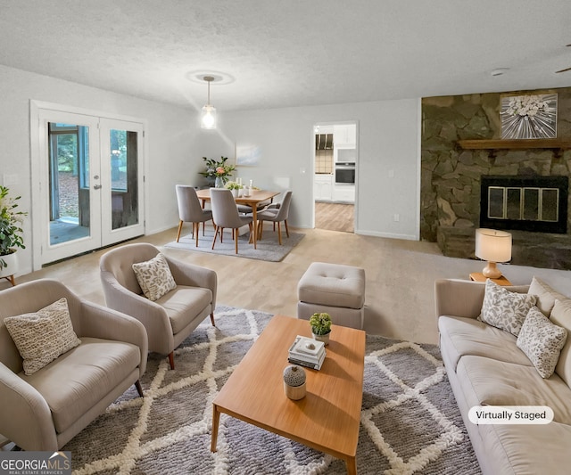 living room featuring french doors, a fireplace, light hardwood / wood-style flooring, and a textured ceiling