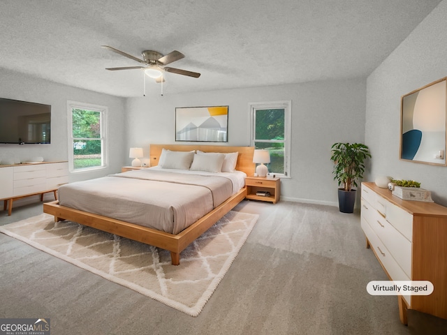 carpeted bedroom featuring ceiling fan and a textured ceiling