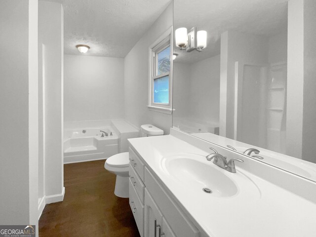 bathroom featuring a textured ceiling, vanity, toilet, and a tub to relax in