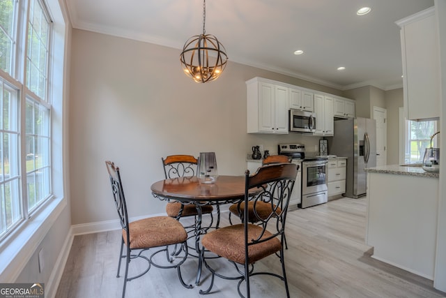 dining area featuring a wealth of natural light, crown molding, light hardwood / wood-style floors, and an inviting chandelier